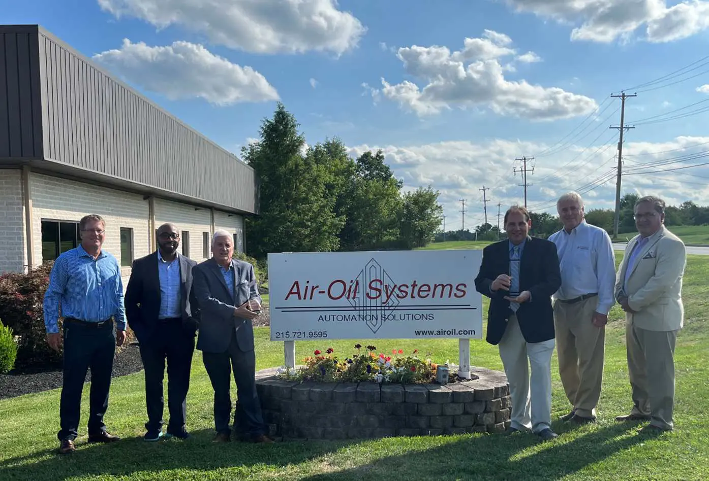 A group of people standing in front of an air-oil systems sign.