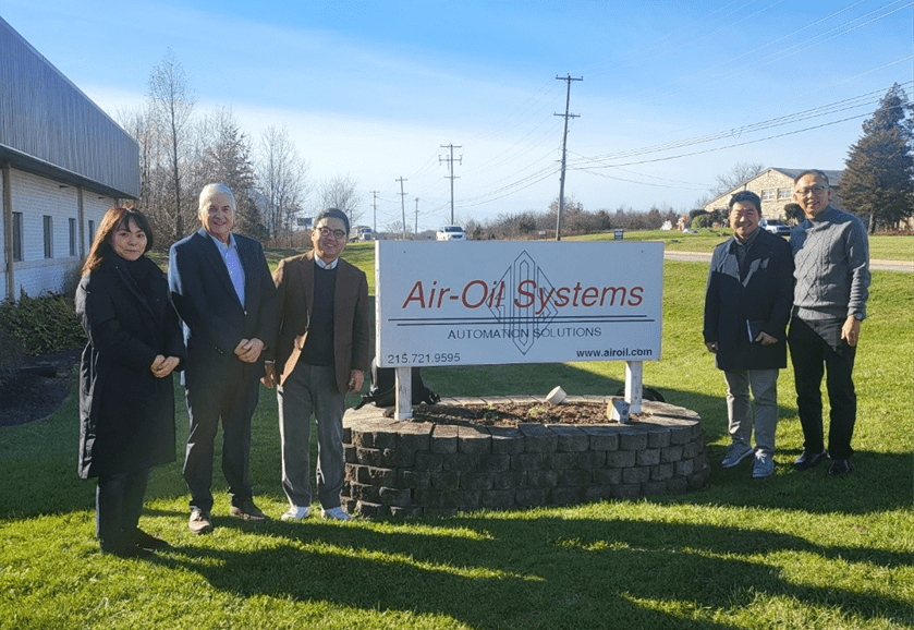A group of people standing in front of an air-oil systems sign.