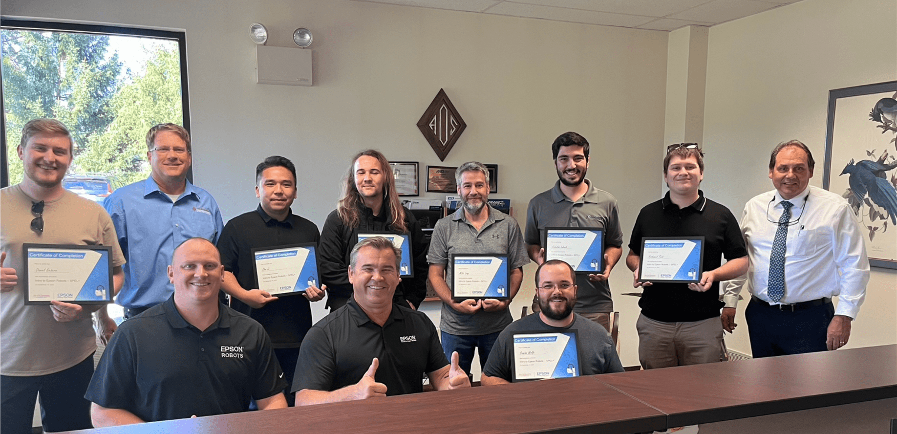 A group of people holding certificates in front of a table.