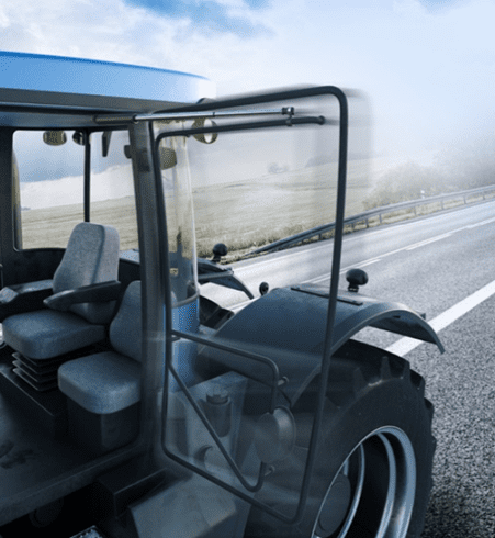 Tractor with an open door on a rural road under a cloudy sky.