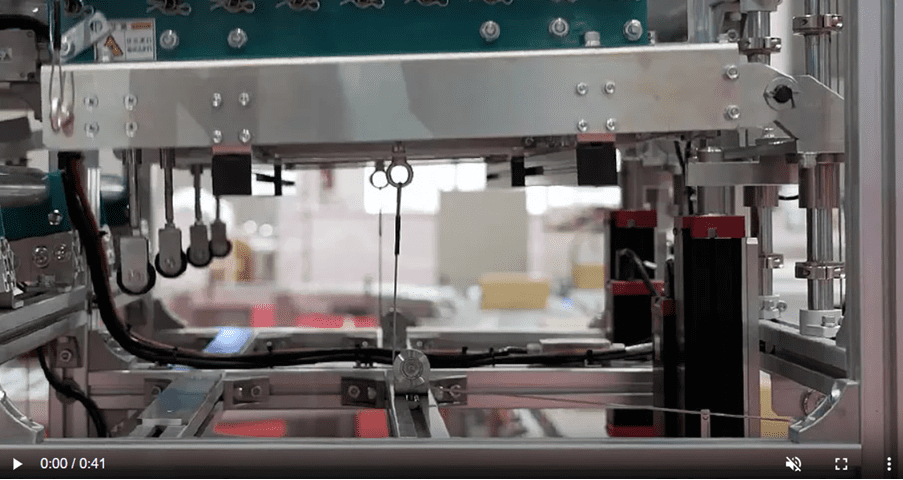 Automated robotic arm picking up cardboard boxes in a warehouse.